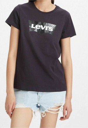 Laivastonsininen puuvillainen t-paita, jossa suuri valkoinen Levi's-logo rinnassa, lyhyet hihat ja rento istuvuus. Näkyvissä kulutetut farkkushortsit.