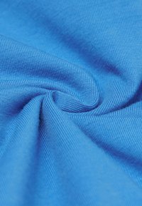 Modrá bavlněná látka s hladkým povrchem, která ukazuje jemně žebrovaný povrch ve spirálovém záhybu.