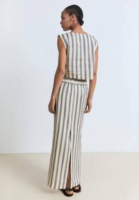 Twee-delige outfit met verticale strepen in beige, blauw en geel. De top heeft een boxy ontwerp; de rok is lang met een zijsplit.