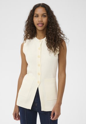 Beżowy bezrękawnik z okrągłym dekoltem, siedmioma guzikami i dwoma przednimi kieszeniami. Dzianinowa struktura, ściągacz na dole i krawędziach kieszeni.