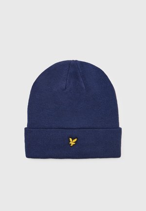 Marineblå strikket beanie-hat med en foldet kant og et gult broderet ørner_logo foran. Blød tekstur, cylindrisk form.