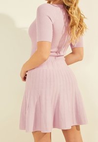 Robe tricotée côtelée de couleur violette claire avec des manches courtes, un corsage ajusté et une jupe évasée. Détails texturés verticaux sur l'ensemble du vêtement.