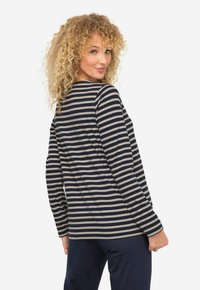 T-shirt à manches longues rayé en marine et beige, avec un col rond et une coupe décontractée. Tissu lisse avec une texture douce et des fentes sur les côtés.
