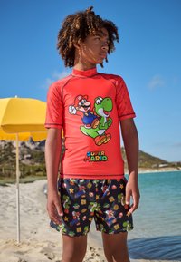 Red rash guard with cartoon graphics of Mario and Yoshi, paired with black swim shorts featuring colorful Super Mario patterns.