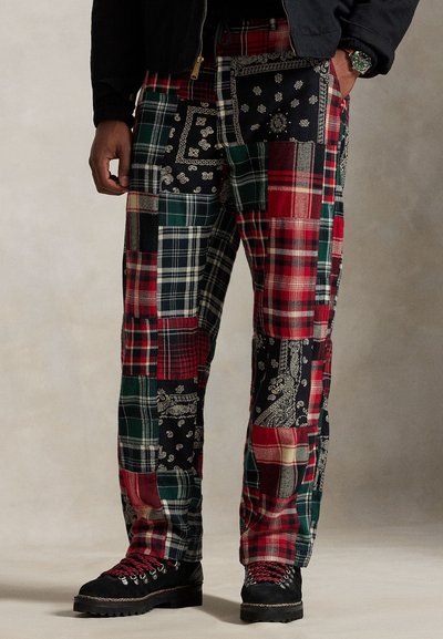 Pantaloni patchwork cu un amestec de modele în carouri roșii, verzi și negre, cu accente de bandană, terminați cu o croială lejeră și buzunare.