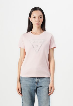 Camiseta de algodón rosa con un gráfico triangular que presenta "GUESS?" en pedrería en el centro. Diseño de mangas cortas y cuello redondo.