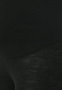 Svarta leggings med ett slätt, något texturerat material och en elegant design med subtil lyster, som övergår mellan två svarta nyanser.