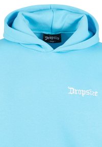 Hellblaue Kapuzenjacke aus weichem Stoff. Sie verfügt über eine vordere Kängurutasche, ein in Weiß gesticktes "Dropsize"-Logo und eine Kapuze mit Kordelzug.