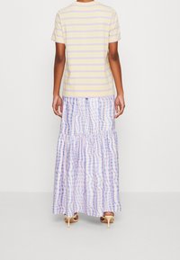 Striped yellow and lavender T-shirt with short sleeves paired with a flowy, plaid maxi skirt in shades of purple and blue.