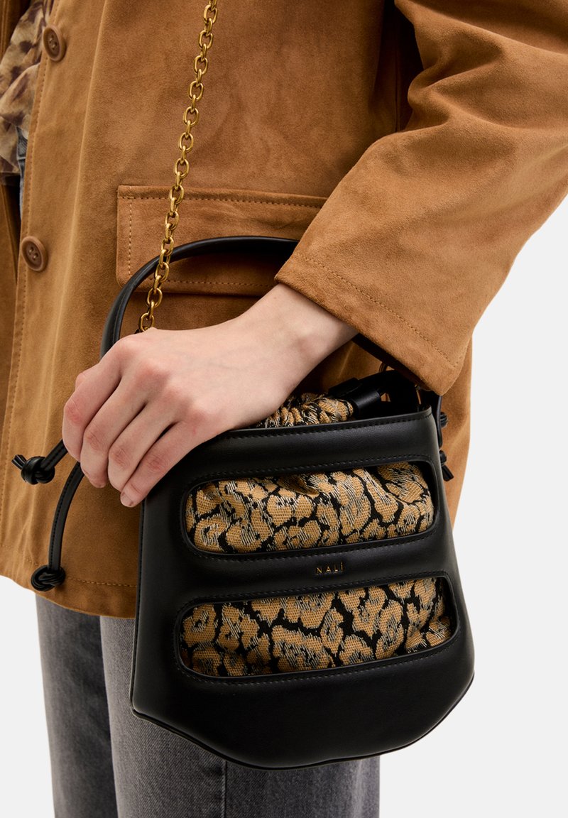 Černá kabelka s texturovanou tkaninou v zvířecím vzoru, řetízkovým popruhem a stahovací šňůrkou. Elegantní design s výraznými detaily na přední straně.