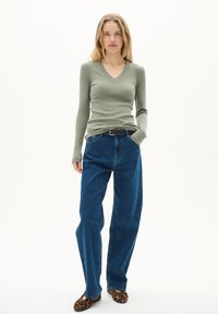 Olivgrön långärmad ribbad topp, högmidjade blå jeans och flats med leopardmönster. Avslappnad passform, med texturerade material och design med v-ringning.