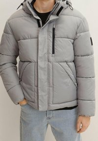 Szara kurtka puchowa z kapturem, z przeszywanymi panelami, kieszenią na piersi zapinaną na zamek, bocznymi kieszeniami oraz elastycznymi mankietami dla zapewnienia ciepła.