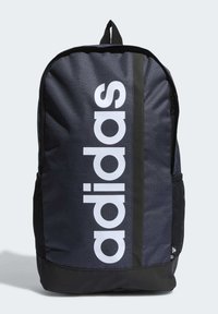 Mochila de tela negra con un gran logo blanco de "adidas", correas ajustables, asa en la parte superior y bolsillos de malla en los laterales para almacenamiento adicional.