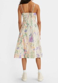 Robe midi fleurie avec bretelles spaghetti, dotée d'un dos smocké, en tissu léger avec des couleurs pastel et des motifs abstraits.