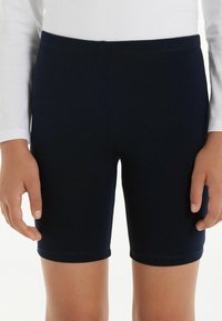 Granatowe szorty stretchy z elastycznym pasem, gładką fakturą i dopasowanym krojem, które kończą się tuż nad kolanem.