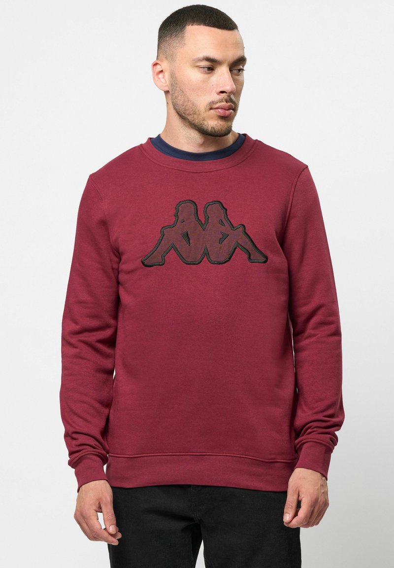 Bordo pulover iz mešanice bombaža, z dolgimi rokavi in okroglim ovratnikom, z črno grafiko na sprednji strani.