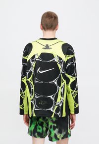 Μακρυμάνικο μπλουζάκι Nike σε μαύρο και νέον πράσινο, με σχέδιο φυσαλίδων και λογότυπο στο πίσω μέρος, κατασκευασμένο από λείο, συνθετικό υλικό.