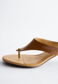 Sandale marron en cuir avec semelle beige carrée et semelle intérieure rembourrée, présentée sur fond blanc.