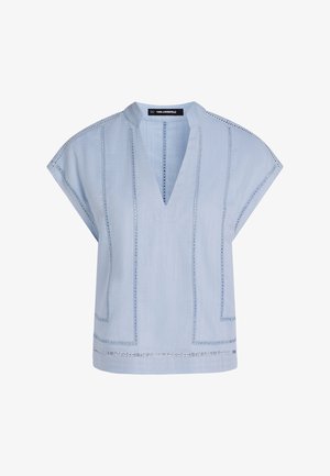 Világoskék blúz V-nyakkivágással, rövid ujjal és díszítő varrással. Dobozos szabással és halvány texturált mintákkal rendelkezik. Vízszintes varratok láthatók.