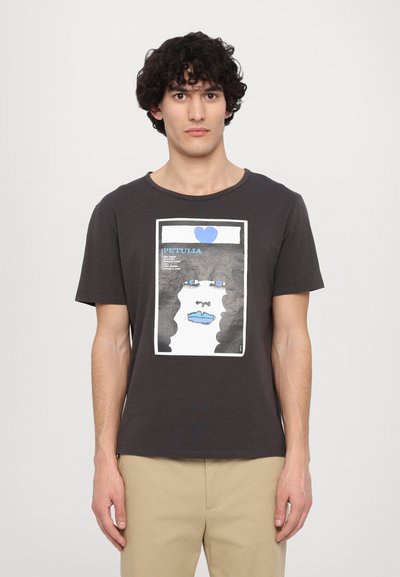 T-shirt en coton noir avec un motif graphique représentant un visage aux lèvres bleues et un cœur bleu en haut. Col rond et manches courtes.