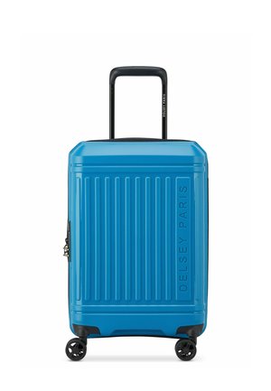 Maleta rígida azul con surcos verticales, detalles en negro, asa retráctil y cuatro ruedas giratorias. Acabado texturizado con el nombre de la marca visible.
