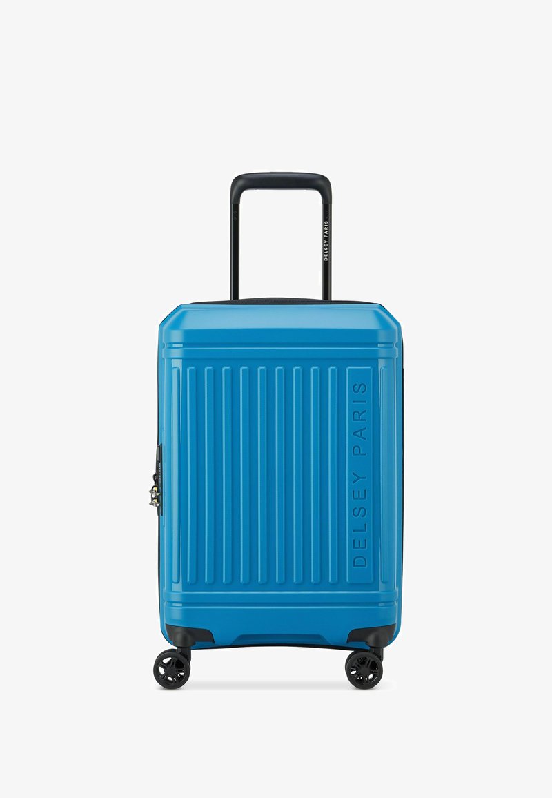 Maleta rígida azul con surcos verticales, detalles en negro, asa retráctil y cuatro ruedas giratorias. Acabado texturizado con el nombre de la marca visible.