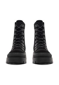 Čierne vysoké topánky z usne, s metalickými očkami, šnurovaním vpredu a masívnymi platformovými podrážkami s textúrovaným detailom.