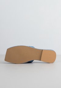 Jasnoniebieski but z plecioną fakturą w cholewce, wyposażony w gładką, beżową gumową podeszwę z wzorzystym bieżnikiem.