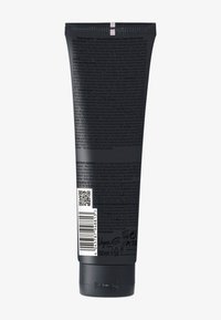 Tube noire à fond arrondi, avec surface texturée, texte blanc et codes-barres, étiquetée comme crème pour boucles, capacité de 150 ml.