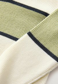 Tessuto in maglia con righe color crema, verde chiaro e blu navy. Superficie testurizzata con dettagli a coste, che presenta bande orizzontali di colore attraverso il materiale.