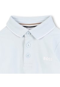 Šviesiai mėlynas polo marškinėlis, pagamintas iš tekstūruotos medžiagos, turintis klasikinį apykaklę, tris mygtukus ir baltą siuvinėtą "BOSS" logotipą.