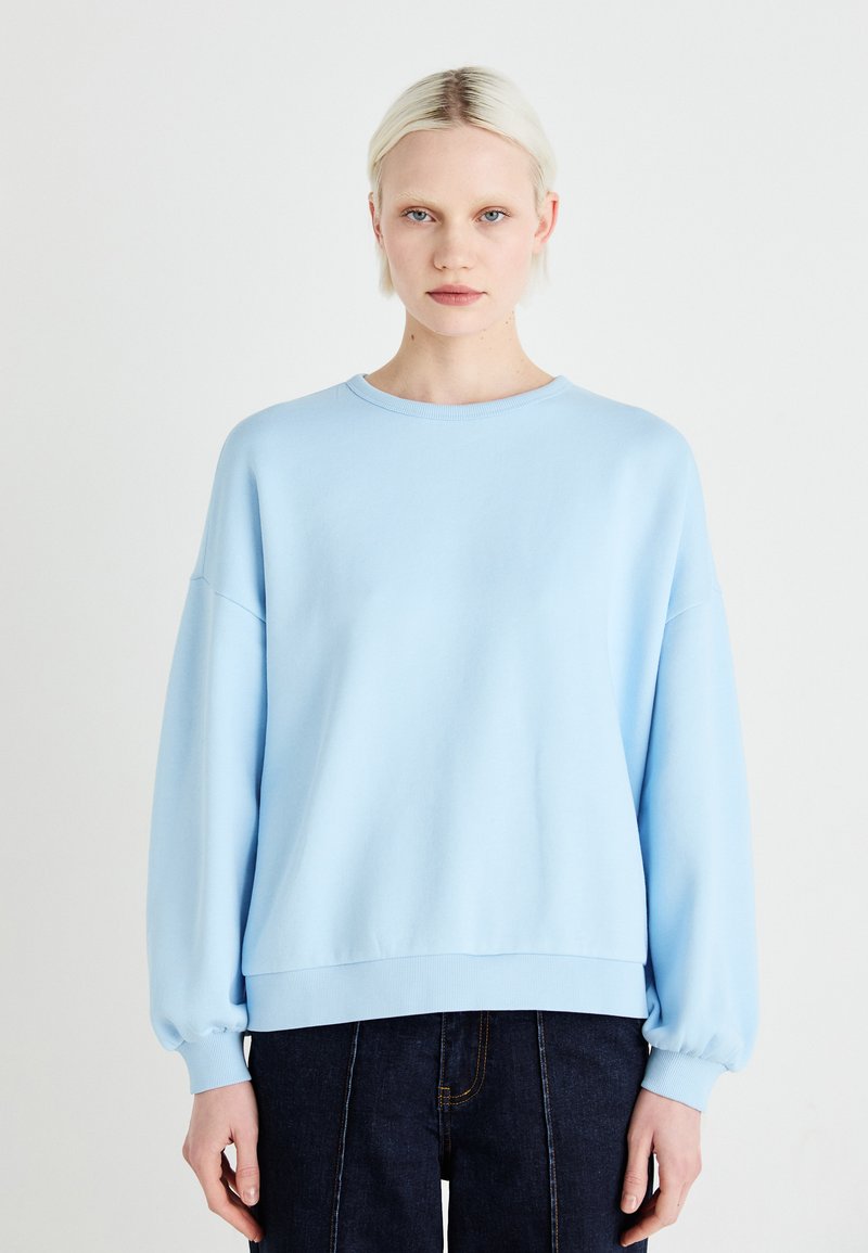 Sweatshirt azul claro com decote redondo, ombros caídos e punhos canelados. Feito de um tecido macio com uma silhueta descontraída.