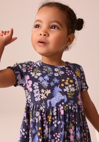 Marinblå klänning med korta ärmar, med ett blommönster och enhörningsmotiv i rosa och blått. Tyget har en ribbad struktur.