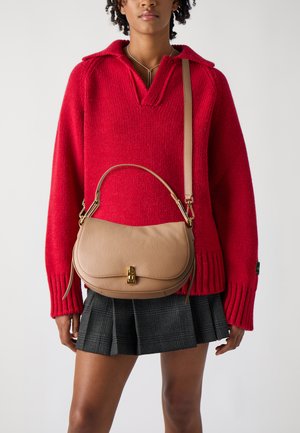 Borsa a tracolla in pelle beige con forma curva e chiusura frontale, completata da una tracolla rimovibile e finitura texturizzata, tenuta in vita.