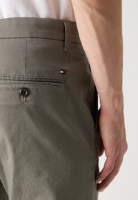 Grønne strukturerede bukser med en baglomme med en mørk knap og en lille logoaccent. Skræddersyet pasform, enkelt design uden synlige mønstre.