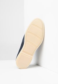 Zapatilla navy con parte superior lisa, suela de goma con fondo beige texturizado y ocho secciones rectangulares para mayor agarre.