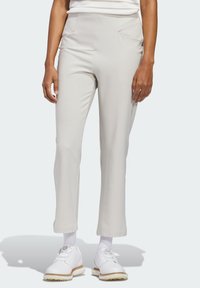 Φωτεινό μπεζ παντελόνι με ομαλή υφή και εφαρμοστή γραμμή. Διαθέτει εμπρόσθιες τσέπες και ελαφριά φούστα στο τελείωμα, συνδυασμένο με λευκά παπούτσια.