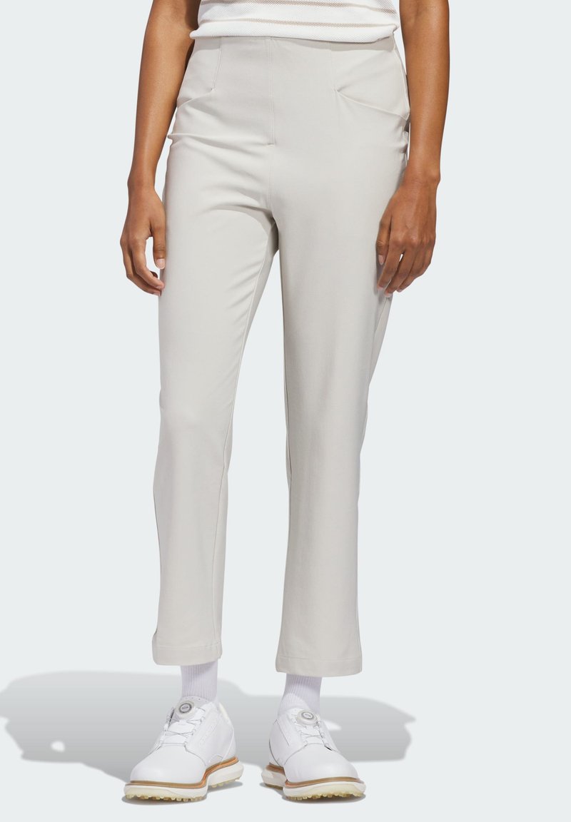 Φωτεινό μπεζ παντελόνι με ομαλή υφή και εφαρμοστή γραμμή. Διαθέτει εμπρόσθιες τσέπες και ελαφριά φούστα στο τελείωμα, συνδυασμένο με λευκά παπούτσια.