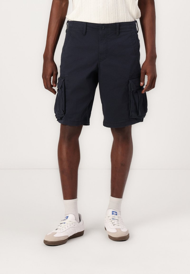 Bermudas de cargo navy avec poches latérales, fabriquées en coton résistant. Présente un design à jambes droites et une taille régulière.