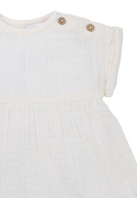 Weißes Kleid aus strukturiertem Stoff, mit einem plissierten Design, kurzen Ärmeln und zwei Holzknöpfen an der Schulter.
