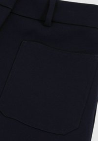 Navyblaue Stoffhose mit einer einzelnen Gesäßtasche mit gestochenem Rand, glatter Textur und einem Gürtelschlaufe am Taillenbund.