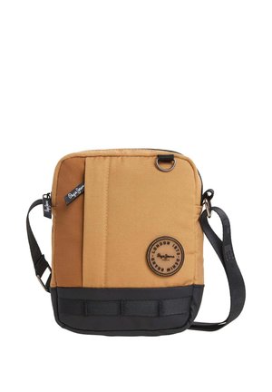 Bolsa mensajera marrón con fondo negro, textura de tela, correa ajustable, cierre de cremallera, parche con logo y bolsillo frontal con un acento a rayas.