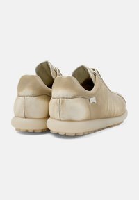Zapatillas metálicas doradas con cuero texturizado, un acabado suave y una suela acolchada que presenta pequeños tacos de goma para mayor tracción.