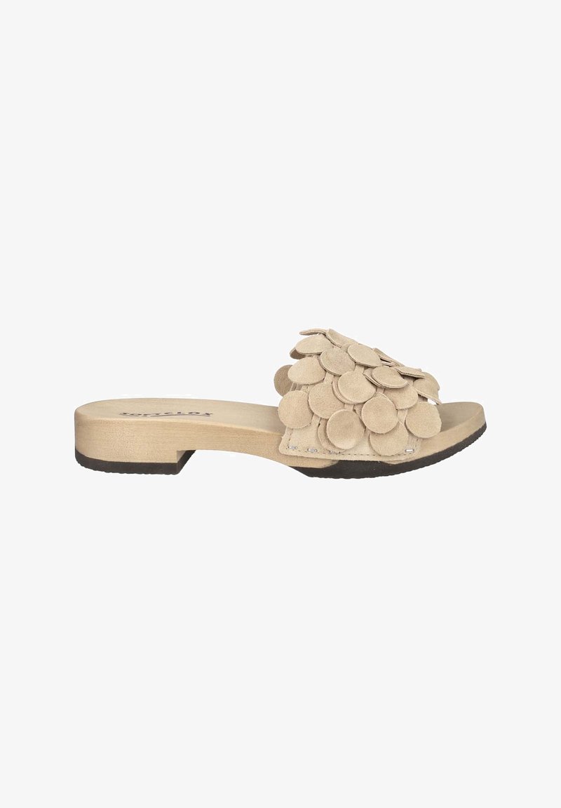 Beige suede slide sandal featuring a textured upper adorned with circular layers and a flat wooden-like sole with a black rubber base.