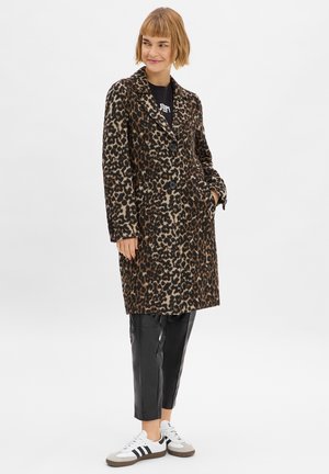 Luipaardprint lange jas in warme, geweven stof, met twee zwarte knopen en zijzakken, gecombineerd met zwarte leren broek en witte sneakers.