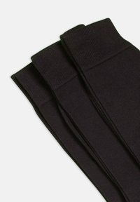Tres pares de calcetines negros acanalados exhibidos de forma plana, con un ajuste ceñido y una textura suave, ideales para el uso casual.