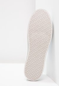 Sola di sneaker bianca con motivo di grip testurizzato, bordi leggermente curvi e una finitura liscia e pulita sul lato superiore. Sfondo chiaro.