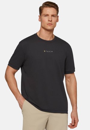 Sort bomulds T-shirt med korte ærmer og rund hals; har et lille guld logo på brystet. Glat tekstur, afslappet pasform.