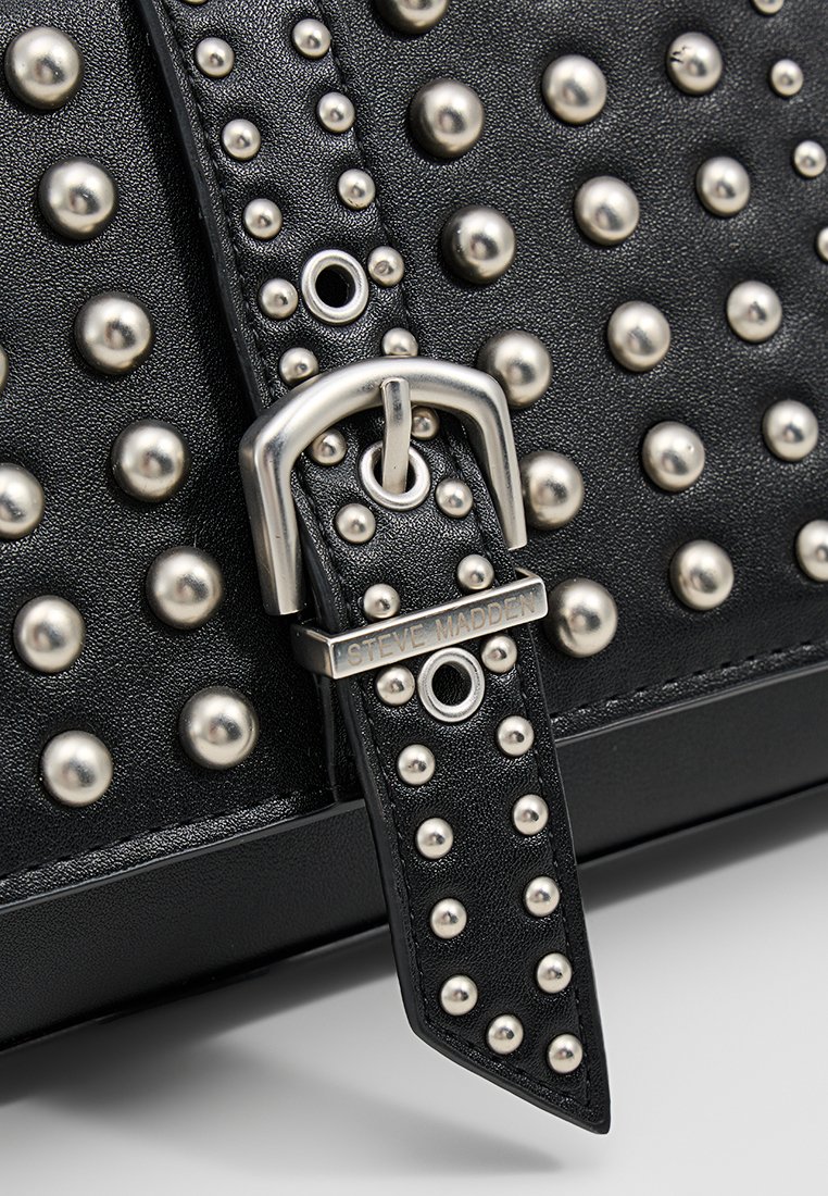 Borsa a tracolla in pelle nera con borchie argentate e dettagli in metallo; la tracolla presenta rivetti decorativi e dettagli di branding.