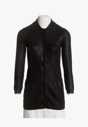 Long cardigan noir en maille avec des boutons sur le devant, deux poches avant, manches longues et col sur un mannequin blanc.